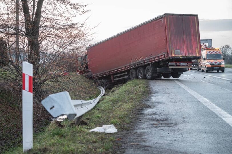 A semi-truck jackknifed off the road with emergency vehicles nearby