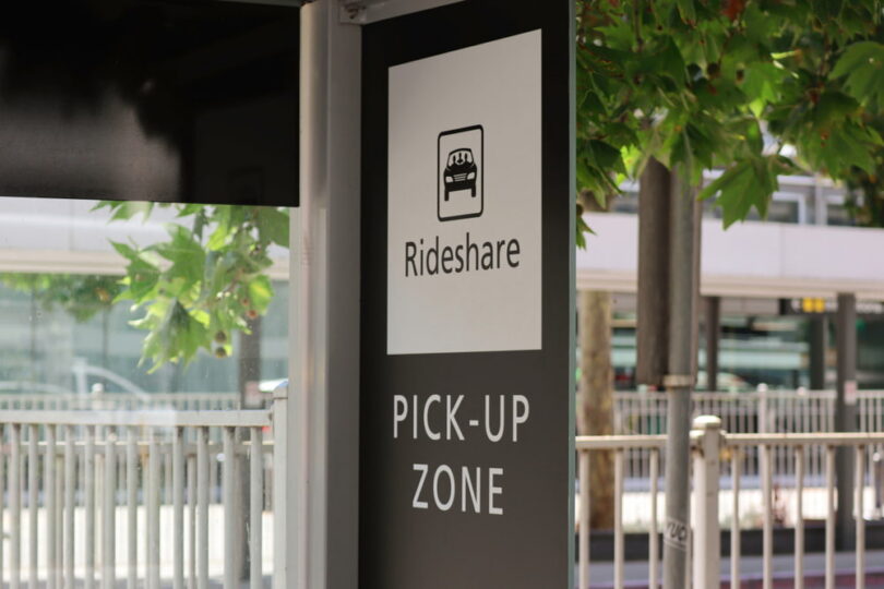 Rideshare pickup zone sign mounted on a post near an airport or transit area