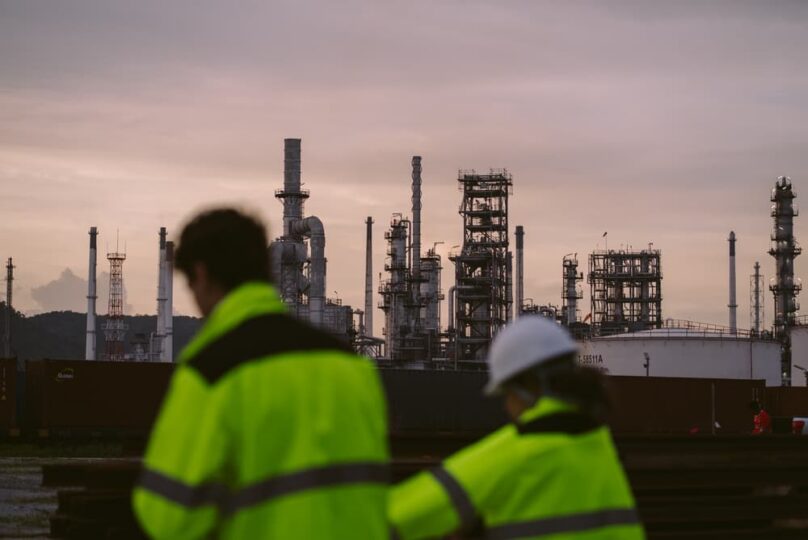 Workers wearing safety gear at an industrial oil refinery facility